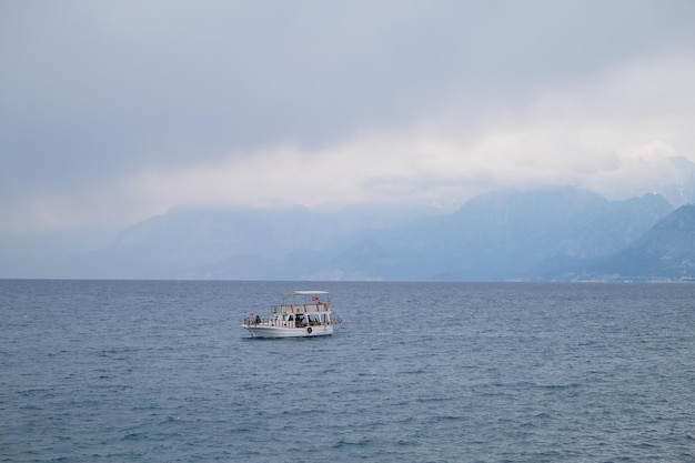 Barco com turistas no mar contra o pano de fundo das montanhas no nevoeiro