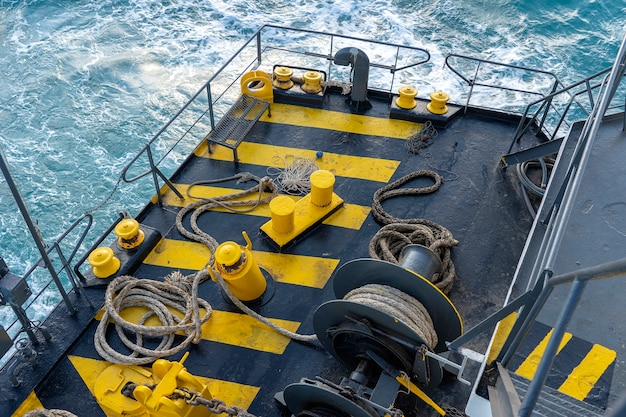 Barco de la cubierta del ferry pintado de amarillo y negro junto con una gruesa cuerda de amarre y una ola de agua de mar azul