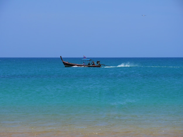 Barco de cauda longa no mar contra o céu claro