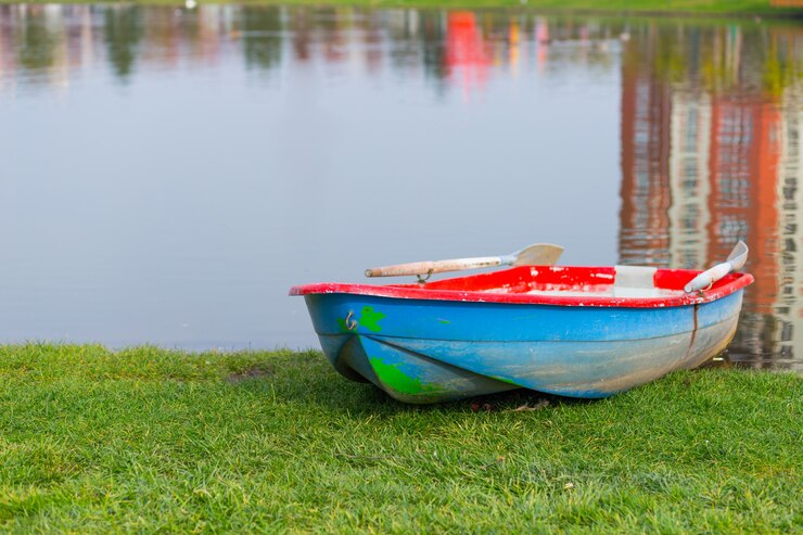 Foto barco de madeira na margem de um lago transparente no parque em um dia quente e claro