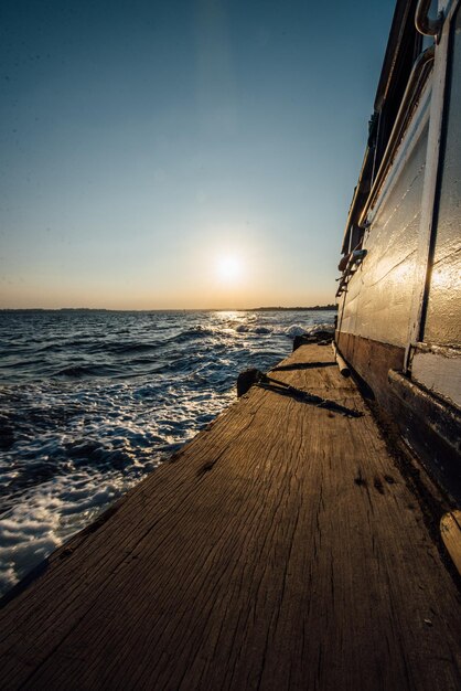 Barco de madeira no mar contra o céu durante o pôr do sol