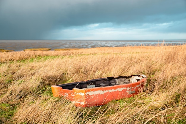 Barco de madeira velho no junco ao lado do mar do norte na ilha Romo na Dinamarca, tempo tempestuoso