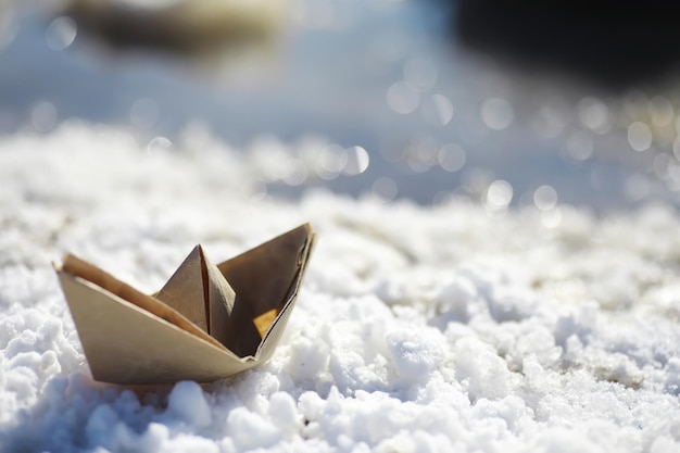 Barco de papel na água na rua. O conceito de início da primavera. Derretendo a neve e um barco de origami nas ondas de água.
