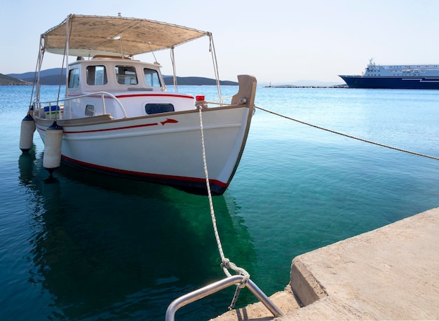 Barco de pesca branco com um toldo no porto da estância grega de Marmari, na Grécia