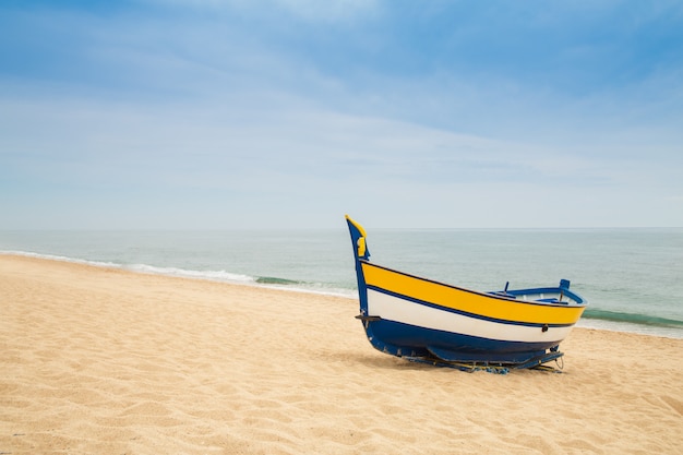 Barco de pesca de madeira em uma praia arenosa