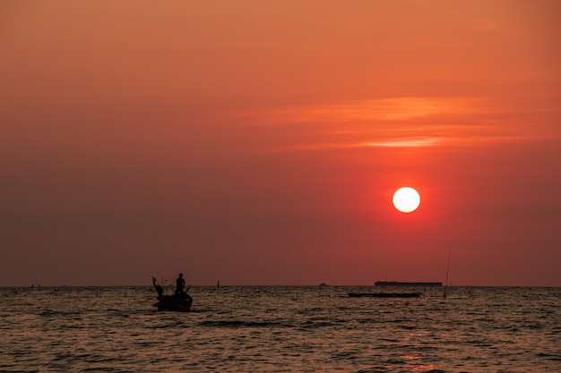 Barco de pesca e pôr do sol à noite e o mar.
