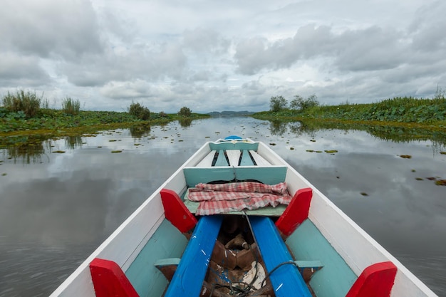 Barco de pesca em um lago de água pela manhãVelho barco de pesca de madeira Barco de pesca de madeira em um lago de água Bela vista da natureza da paisagem em Thale noi Phatthalung Tailândia