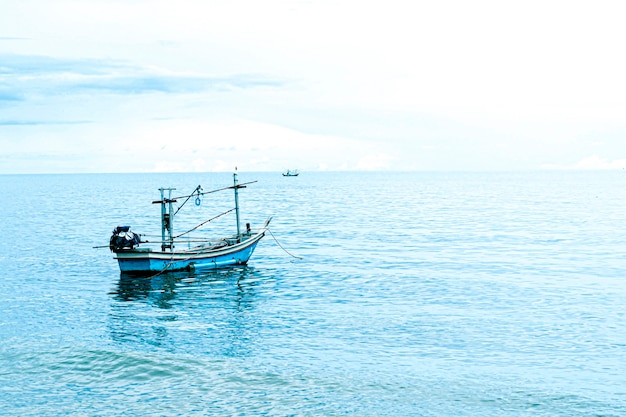 Barco de pesca pequeno flutuando no mar azul com céu azul, barco de pesca da Tailândia ou barco de pescador ou navio na praia de Sam Roi Yod Prachuap Khiri Khan Tailândia com céu azul e nuvem e mar azul