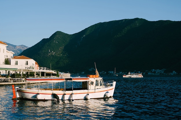 Barco de recreio em branco perto das montanhas de Perast.