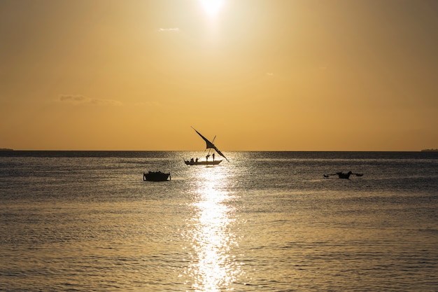 Barco dhow de pescador tradicional durante la puesta de sol en el océano Índico en la isla de Zanzíbar, Tanzania, África Oriental