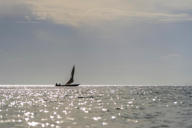 Barco dhow de pescador tradicional durante la puesta de sol en el océano Índico en la isla de Zanzíbar, Tanzania, África Oriental