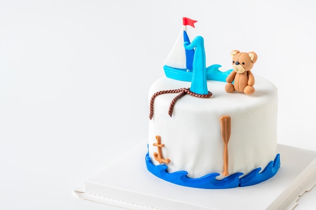 Barco e boneca urso fondant no bolo de baunilha no fundo branco