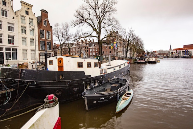 Un barco está atracado en un canal con un pequeño bote en primer plano Amsterdam