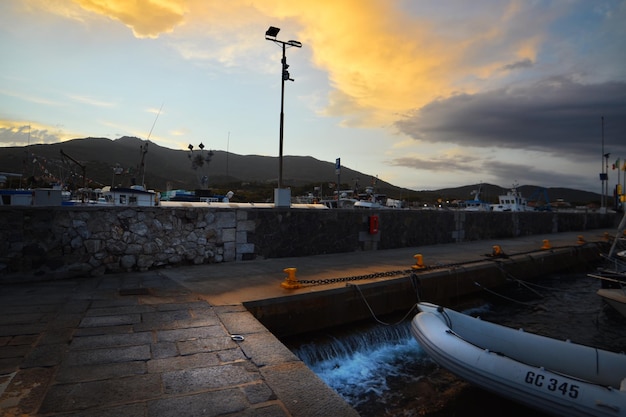 Un barco está atracado en un puerto deportivo con una montaña al fondo.