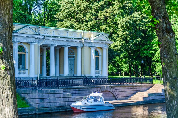 Foto un barco está estacionado frente a un edificio con un puente al fondo.