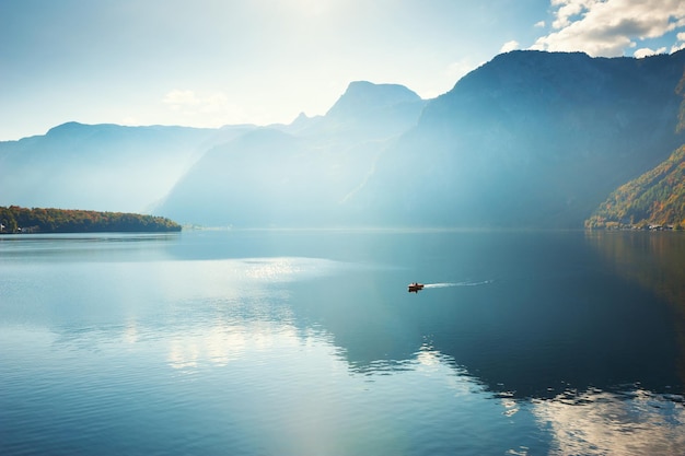 Barco flutuando no lago hallstatter nas montanhas dos alpes, na áustria. linda paisagem de outono