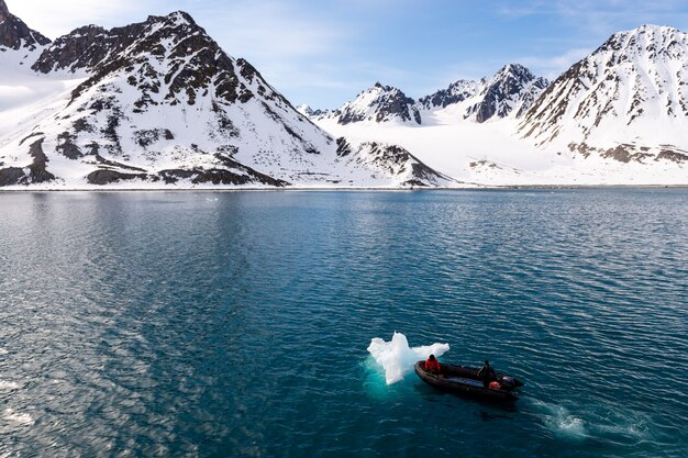 Barco inflável com uma pessoa nas águas do Ártico, Svalbard. Empurrando gelo.