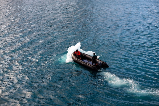 Barco inflável com uma pessoa nas águas do Ártico, Svalbard. Empurrando gelo.