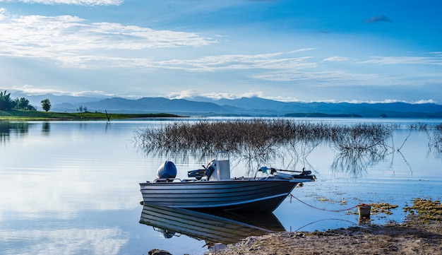 Barco en un lago de montaña con luz solar. Lago natural de la presa en bosque.