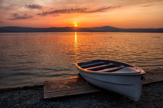 Barco en el lago con el telón de fondo de una pintoresca puesta de sol