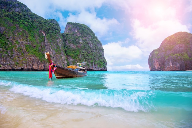 Foto barco longo e água azul na baía maya na ilha phi phi, krabi tailândia.