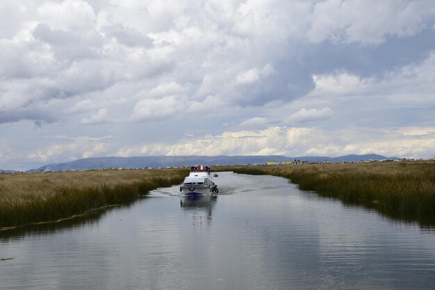 Un barco con lugareños paseos a lo largo de un pequeño canal en el lago Titicaca a las islas de paja Puno Perú