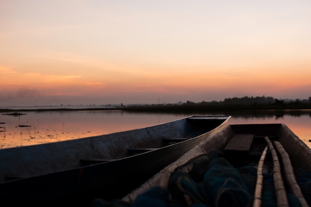 Barco de madera amarrado en el río con la puesta de sol