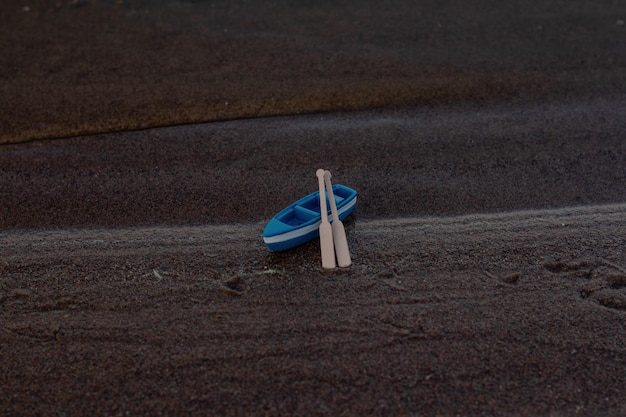 Barco de madera azul se encuentra en la orilla con remos