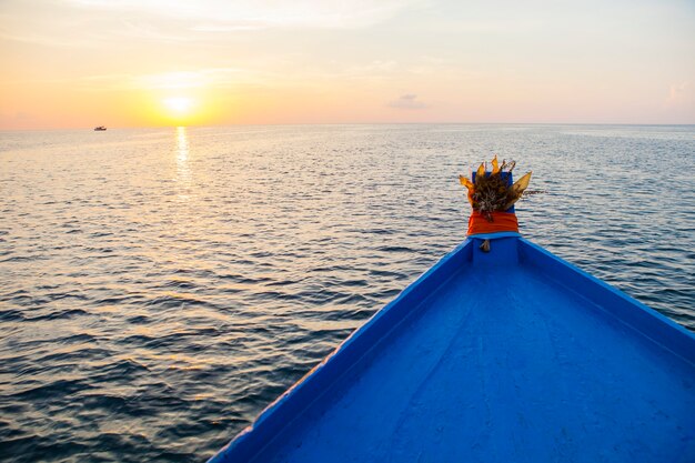 barco de madera azul navegando en agua de mar contra el hermoso cielo al atardecer