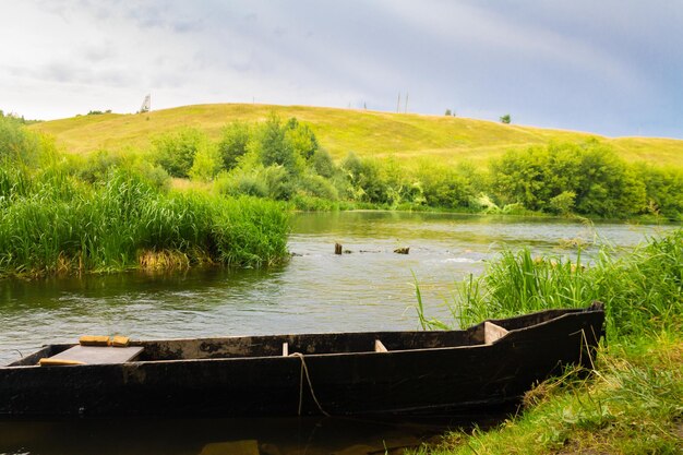 Barco de madera en el fondo de la naturaleza salvaje del río Pesca en un día soleado de verano