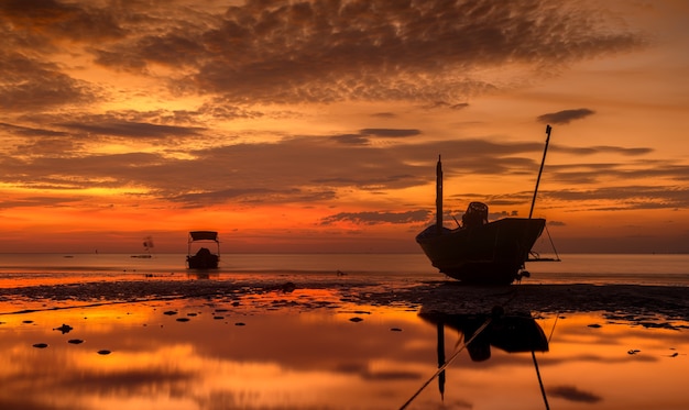 Barco de madera de la pesca de la silueta con la iluminación tenue del cielo del atardecer y la sombra oscura.