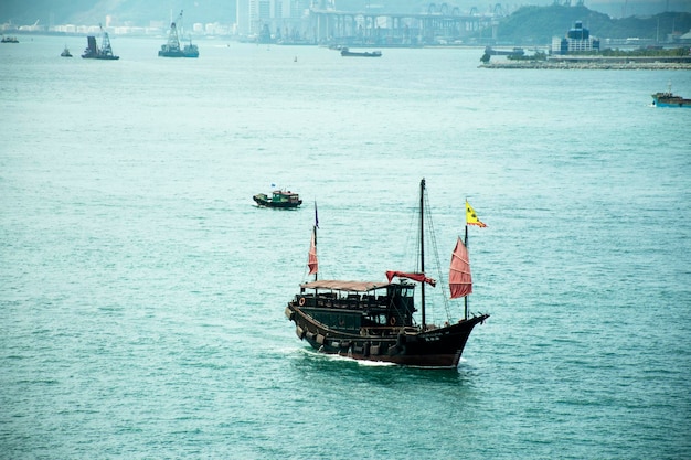 Barco de madera retro o barcos basura chinos para viajeros que miran la vista de Hong Kong y la isla de Kowloon en el puerto de Victoria el 3 de septiembre de 2018 en Hong Kong, China