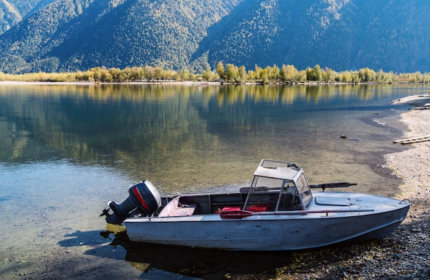 Barco de motor viejo cerca de la orilla del lago de montaña. Otoño. Rusia, Altai, Lago Teletskoye