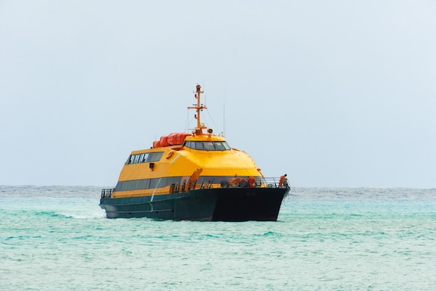Un barco naranja navega en el mar en un día nublado Yate de dos pisos en el mar