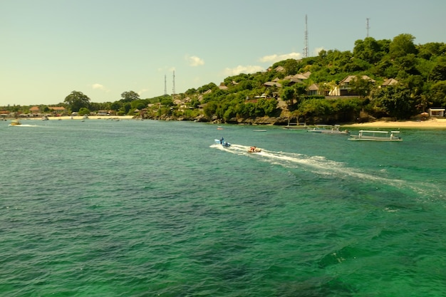 Un barco navega en el agua frente a una playa.