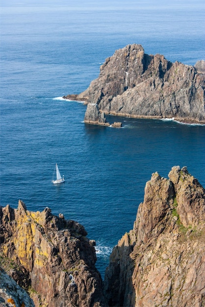 Un barco navega en el océano cerca de las rocas.