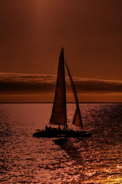 Barco navegando en el mar contra el cielo durante la puesta de sol