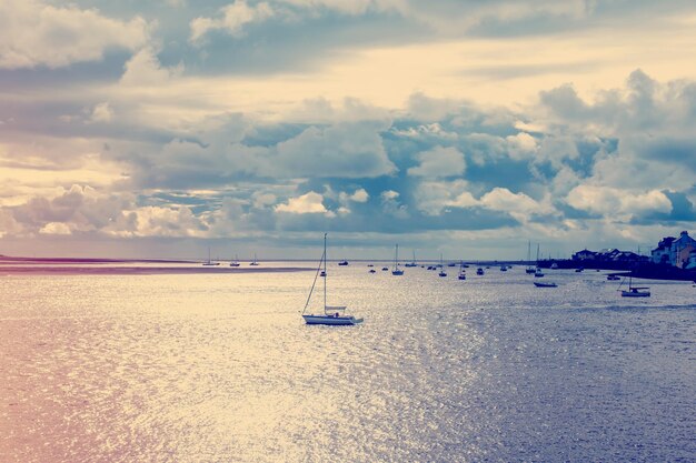 Barco no mar contra céu nublado ao pôr do sol