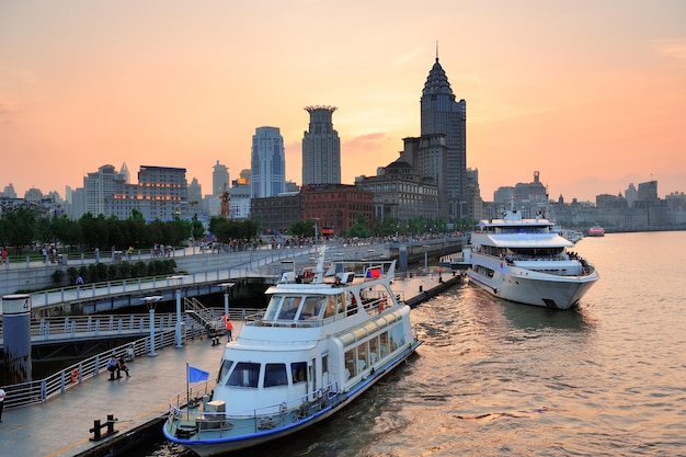 Barco no Rio Huangpu com arquitetura urbana de Xangai ao pôr do sol na doca