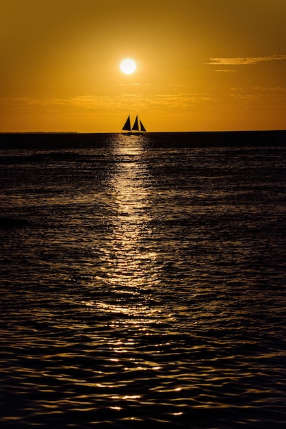 Barco en el océano al atardecer veleros con velas yate de mar navegando por el agua