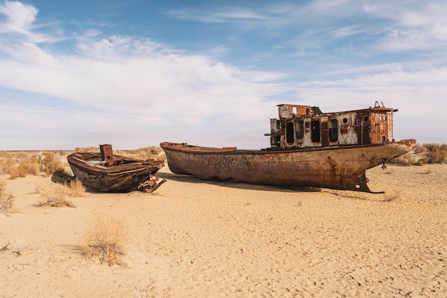 Foto barco oxidado en el fondo del antiguo mar de aral el mar seco en un desastre ambiental y el cambio climático en asia central problemas del concepto de calentamiento global