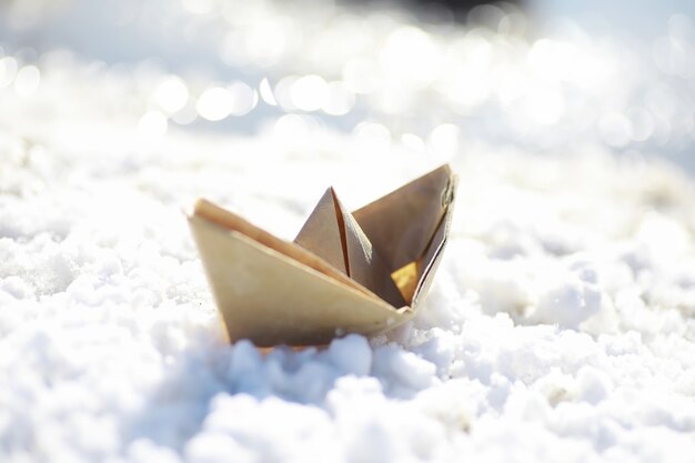 Barco de papel en el agua en la calle. El concepto de principios de la primavera. Derretimiento de la nieve y un barco de origami sobre las olas del agua.