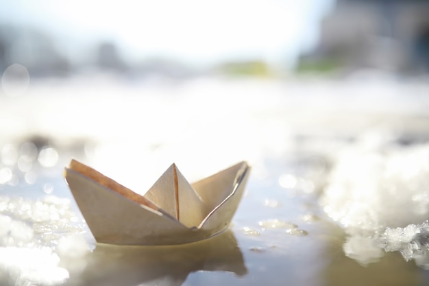Barco de papel en el agua en la calle. El concepto de principios de la primavera. Derretimiento de la nieve y un barco de origami sobre las olas del agua.
