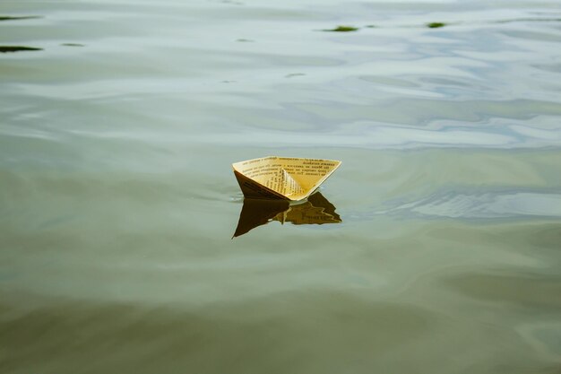 Un barco de papel blanco flotando en el agua