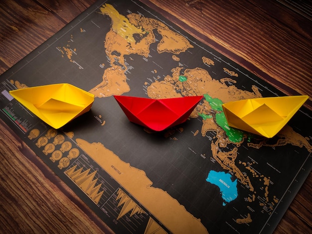 Barco de papel de colores y mapa del mundo sobre una mesa de madera