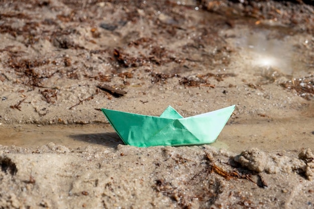 Barco de papel de origami multicolor en un arroyo o charco Un símbolo de la infancia o un trozo de luz en el mundo oscuro