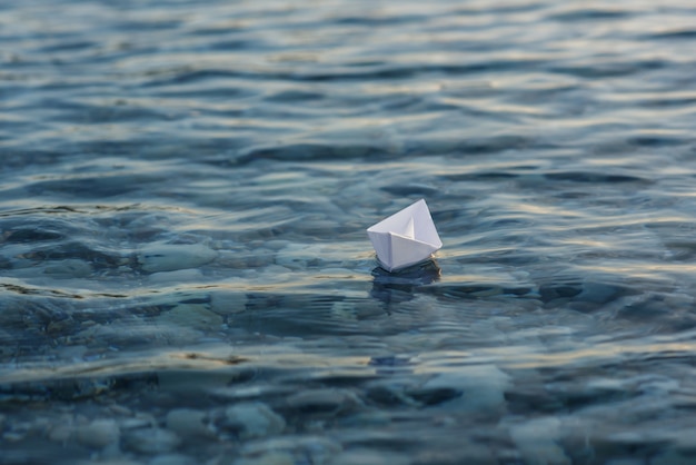 Barco de papel origami navega en la superficie del agua