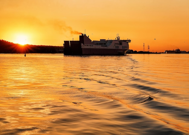 Barco de pasajeros en el mar Báltico en el puerto de Klaipeda, Lituania. Sol y luz dorada al atardecer.