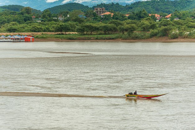 Barco de pasajeros en el río Mekong con niebla y fondo de montaña