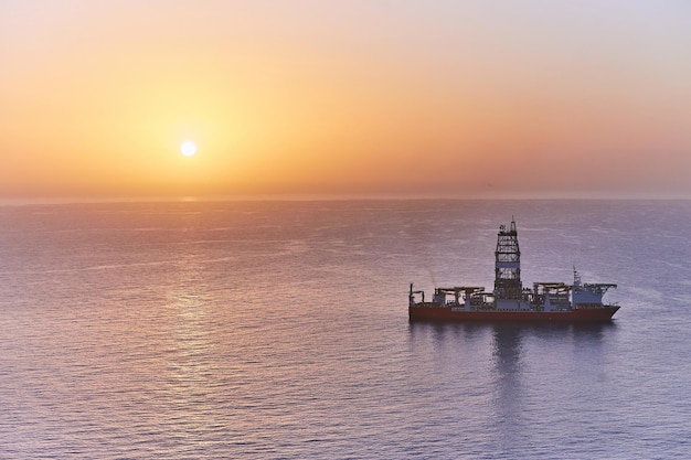 Barco de perforación plataforma oceánica de fondo de pozo de petróleo de perforación. Campos de petróleo y gas de exploración geológica en el mar al atardecer